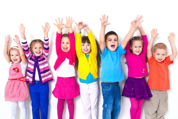 Zdjęcie przedstawia siódemkę uśmiechniętych dzieci z rączkami do góry